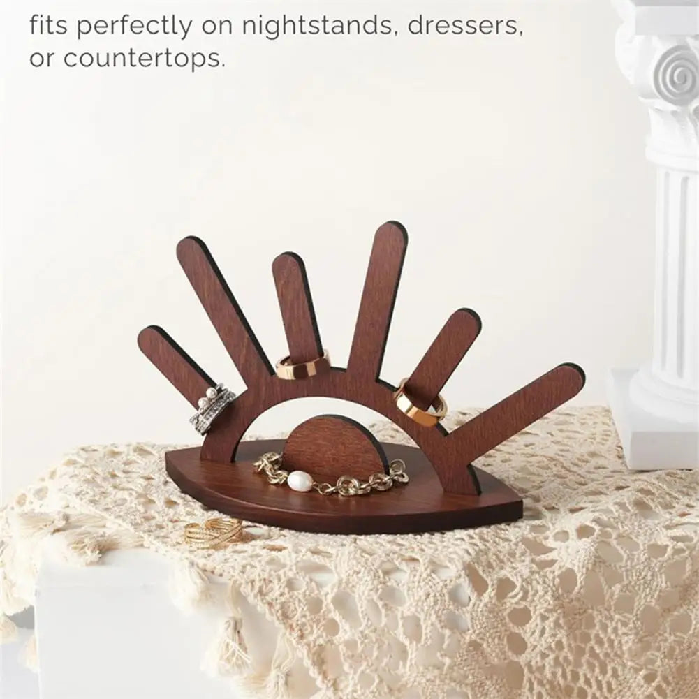 Wooden jewelry holder with rings and bracelets on a lace tablecloth.