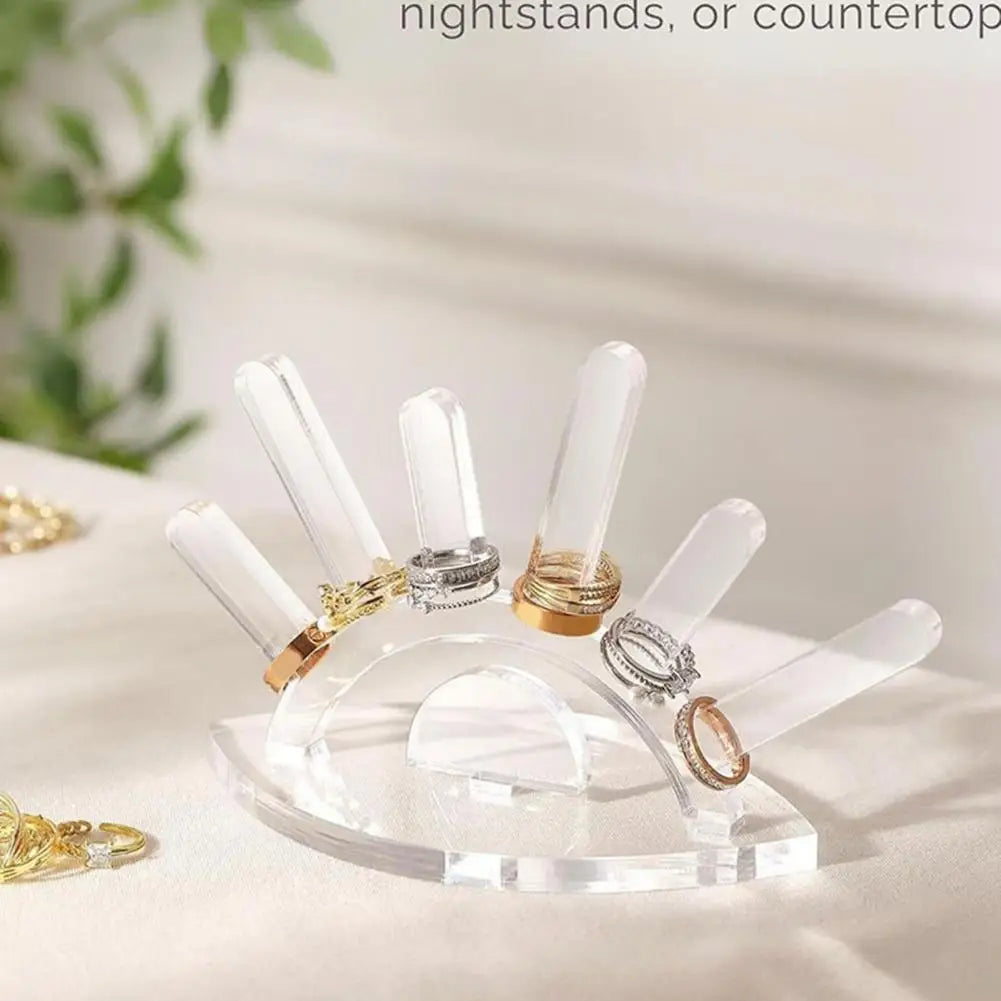 Clear acrylic ring holder with gold and silver rings on a white surface.