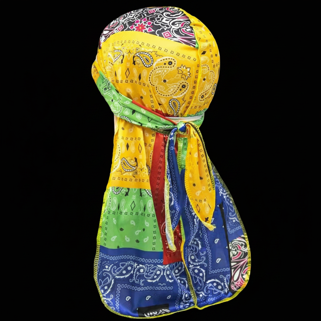 A multicolor patchwork bandana durag headwrap displayed on a black background. The wrap features various patterned fabric panels including yellow paisley, green florals, blue paisley, and red accents.